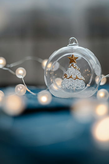 kerst versiering, transparante bal, decoratief glas, kerstboom, feestelijke lichten, soft-focus, vakantie decor, glazen ornament, winter decoratie, kerst decoratie, delicaat ornament
