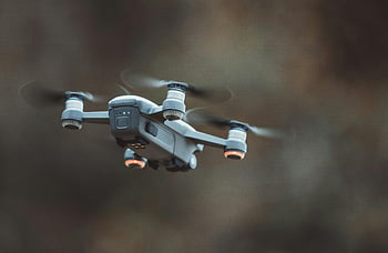 Grey Quadcopter Drone, close-up drone, outdoor drone, drone technology, flying drone, detailed drone, quadcopter design, outdoor setting, drone photography, aerial drone, drone flight