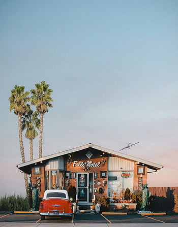 hotel, dinding kayu, pohon-pohon palem, Motel vintage, mobil merah klasik, langit biru jernih, fasad yang menawan, motel retro, adegan di luar ruangan, tujuan perjalanan, daya tarik pinggir jalan