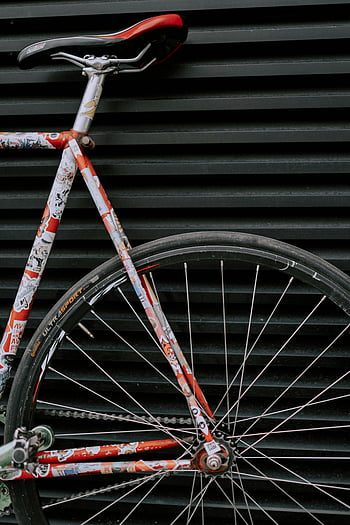 red bicycle, black wall, close-up, colorful bicycle, striped background, bike details, bicycle frame, bicycle wheel, bicycle tire, urban setting, bicycle design