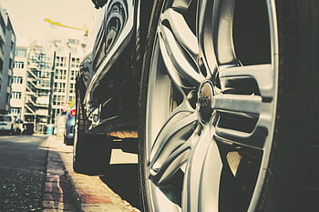 car wheel, city street, urban vibe, parked car, building background, cityscape, urban scene, car detail, street parking, modern city, car reflection