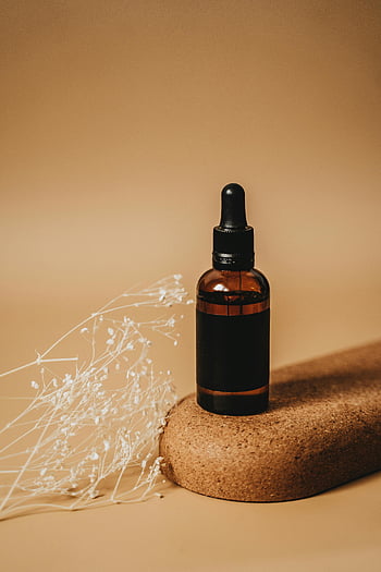 brown glass dropper bottle, amber glass bottle, cork surface, dried flowers, stylish bottle, natural cork, delicate flowers, dropper bottle, brown surface, minimalist setup, essential oil bottle