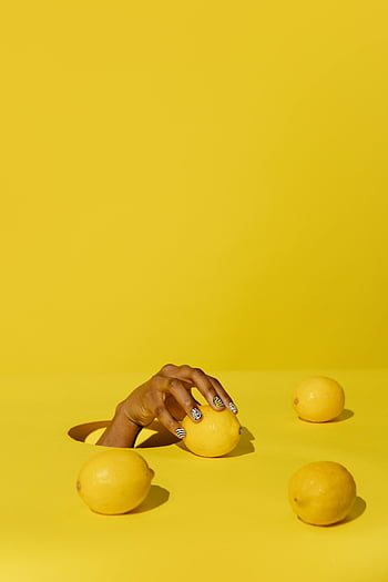 hand holding lemon, yellow background, citrus freshness, vibrant creativity, lemons, yellow surface, nail art, minimalist composition, fruit photography, bright colors, still life