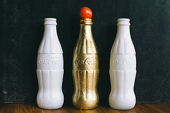 lahví, Bílé láhve Coca-Cola, Brass Coca-Cola Bottle, Zlaté centrum, Top rajčata, dřevěný povrch, Stylizovaná Coca-Cola, dekorativní láhve, Vintage Coca-Cola, sběratelské láhve, Unikátní design Coca-Cola