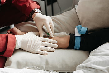 medical professional, inserting needle, intravenous line, patient's arm, clinic setting, gloves, medical gloves, healthcare, medical procedure, patient care, intravenous therapy