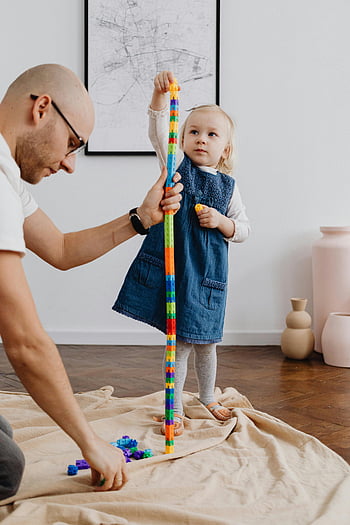 父娘の遊び時間、 スタッキングおもちゃ、 カラフルなブロック、 室内遊び、 家族の絆、 ブロックタワーゲーム、 子どもの発達、 遊び心のある学習、 親子の相互作用、 屋内アクティビティ、 教育のおもちゃ