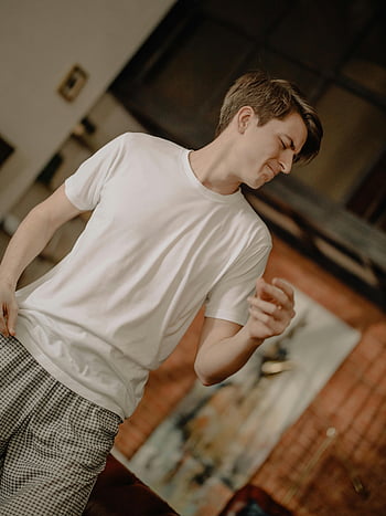 ung mand, hvid besætning hals t-shirt, Sort og hvid rutede bukser, Hyggelige hjemmeindstillinger, afslappet tøj, fritidsøjeblik, indendørs scene, afslappet positur, Komfortabelt tøj, afslappet mode, Hjemmemiljø