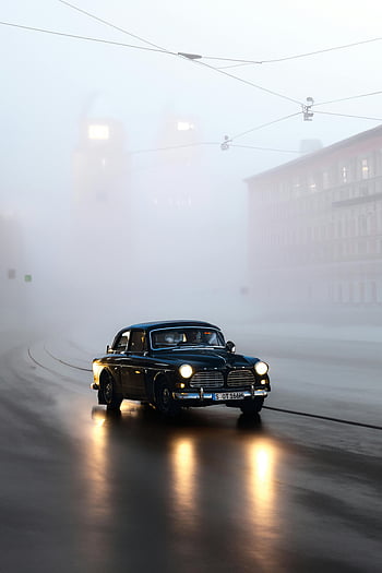 Volvo Amazon, classic car, foggy street, moody atmosphere, city street, vintage car, driving through fog, urban scene, classic Volvo, foggy atmosphere, street scene