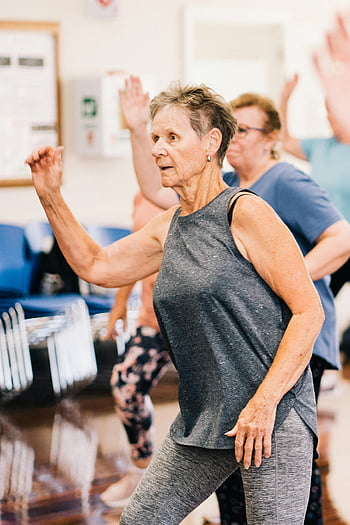 elderly woman, gray tank top, leggings, exercising, senior women, dancing, fitness class, healthy lifestyle, group exercise, active seniors, indoor workout
