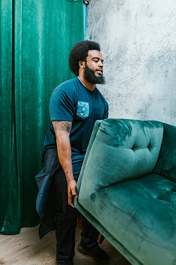 bearded man, carrying, green couch, teal velvet couch, moving service, relocation service, furniture moving, man with beard, indoor setting, professional mover, velvet couch
