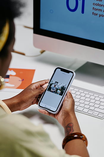 detailní záběr, osoba používající mobilní telefon, ruce drží smartphone, Procházení fotografií, pozadí počítače, chytrý telefon, počítač, lavice, Nastavení kanceláře, prohlížení fotografií, využití technologie