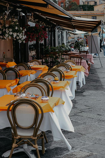 outdoor cafe, vibrant orange tablecloths, elegant chairs, city street, inviting outdoor seating, restaurant tables, empty tables, street cafe, urban dining, outdoor dining, restaurant exterior