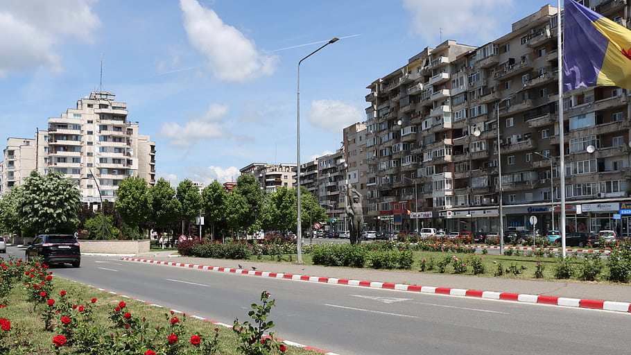 Deva, Romania, cityscape, apartment buildings, street view, flag, statue, trees, flowers, blue sky, clouds