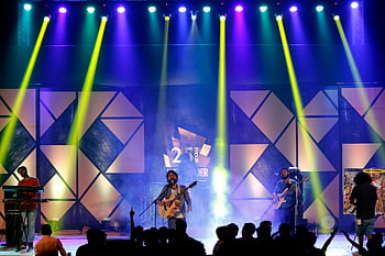 Live Band Performance, mand spiller guitar, synger på scenen, Dynamisk belysning, nat koncert, energisk præstation, scene præstation, Live musik, koncert stadium, publikum, farverige lys