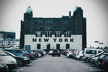 New York Hotel, parking lot, cars, building, bold New York text, urban scene, cityscape, vehicle parking, architectural signage, motel, street view