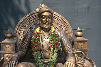 shivaji maharaj, estátua de bronze, guirlanda floral, flores vibrantes, luz do dia, figura histórica, história indiana, herança cultural, traje real, jóias tradicionais, Postura sentada
