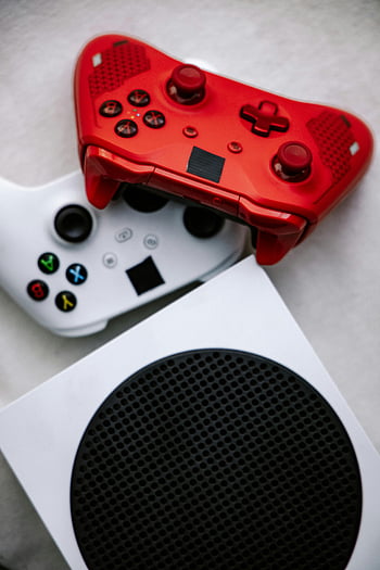 Videospielkonsole, Red Game Controller, weißer Gamecontroller, Nahaufnahme, Moderne Konsole, leuchtend rot, vertikaler Schuss, Spielzubehör, Gaming -Controller, Spielkonsole, Spiel-Setup