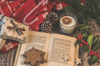 Weihnachtsszene, Festliche Atmosphäre, offenes Buch, Ein Glas Milch, Feiertagsdekorationen, gemütliche Einstellung, Traditionelles Weihnachten, Kiefernzapfen, Zuckerstange, Geschenke, roter Pullover