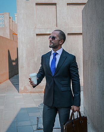 mand i dragt, hvid kaffekop, Professionel forretningsmand, Gå udendørs, Dubai, solbriller, mappe, bymæssige omgivelser, Stilfuldt outfit, moderne by, Professionel påklædning