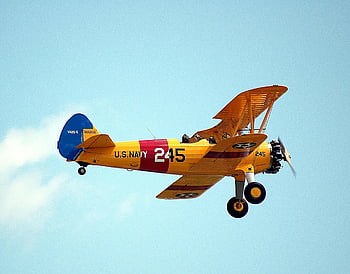 Vintage americký námořnictvo biplane, Klasický letecký design, jasné modré nebe, letadlo letící, Letadlo amerického námořnictva, Biplane za letu, historie letectví, Klasické letadlo, vinobraní letadla, nebe pozadí, Letadlo námořnictva USA