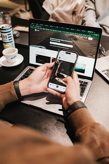 Mâinile care dețin smartphone, laptop, multifunctional, tehnologie, persoană care utilizează smartphone-ul, persoană care utilizează laptop, utilizare simultană, productivitate, dispozitive digitale, configurare de lucru, cană de cafea