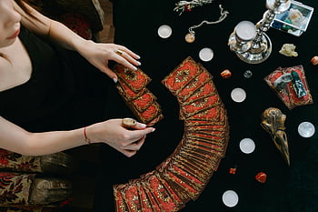 tarot card reading, mystical scene, fortune insights, candles, woman spreading cards, tarot cards, table, mystical objects, fortune telling, crystal balls, mystical atmosphere
