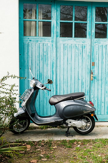 Vespa, motor scooter, parked, turquoise door, vintage style, vibrant color, classic Vespa, weathered door, scooter, front door, outdoor scene