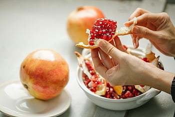 pomegranate, peeling pomegranate, vibrant red seeds, kitchen setting, close-up hands, ripe pomegranate, pomegranate seeds, peeling seeds, kitchen scene, fruit preparation, healthy eating