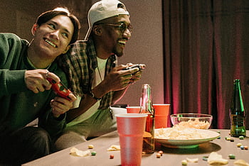 mannen die videogames spelen, videogameavond, vrienden gamen, snacks en drankjes, Home Gaming, Videogame -controllers, Casual gaming, gaming-opstelling, Vrienden genieten, binnengamen, Gaming Buddies