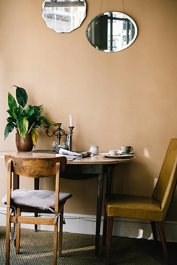 kulatý hnědý dřevěný stůl, hnědé židle, Vintage židle, Rustikální jídelna, Vřelé pozvání stolování, rostlin, zrcadla, Vintage stůl, Výzdoba jídelny, Útulný jídelní prostor, rustikální nábytek