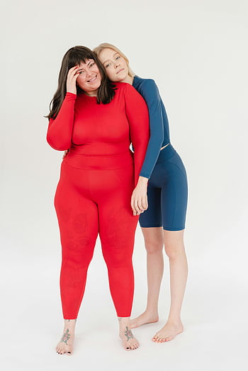 cheerful women, different body types, red activewear, blue activewear, embracing, smiles, studio setting, activewear fashion, body positivity, diverse beauty, healthy lifestyle