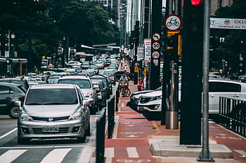 urban street, kraftig trafik, cyklister, Bustling City, parkeret grå bil, bymiljø, trafikprop, gadescene, byliv, bytransport, cykelbane