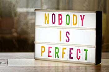 illuminated text box, lightbox, motivational slogan, nobody is perfect, colorful letters, display sign, inspirational quote, indoor setting, table surface, bright lighting, motivational message