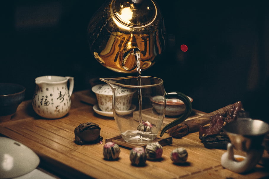 tea ceremony, golden teapot, wooden table, artistic capture, utensils, clear glass pitcher, tea setup, tea preparation, cultural tea, tea art, tea culture
