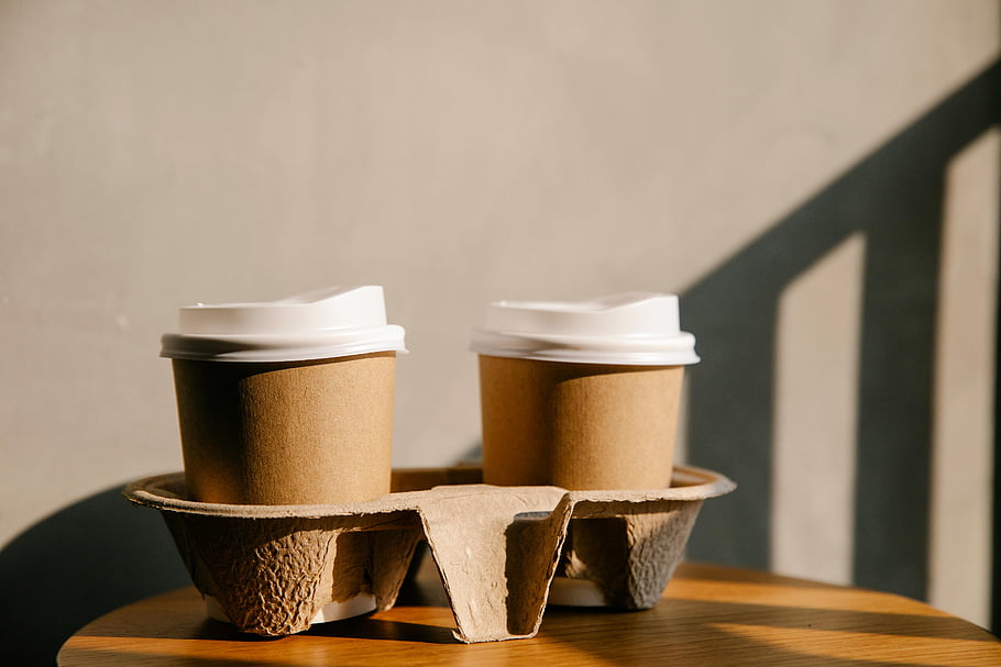 cardboard cups, holder tray, table, disposable coffee cups, soft sunlight, shadows, eco-friendly packaging, sustainable packaging, takeaway cups, coffee cup holder, eco-friendly coffee cups
