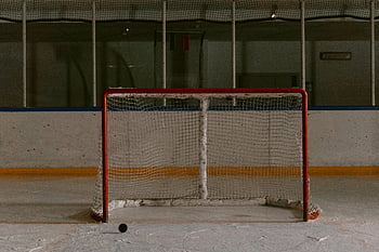 ice hockey rink, empty goal net, puck on ice, metal bar, net on ice, ice surface, hockey goal, indoor rink, sports equipment, ice hockey equipment, hockey net