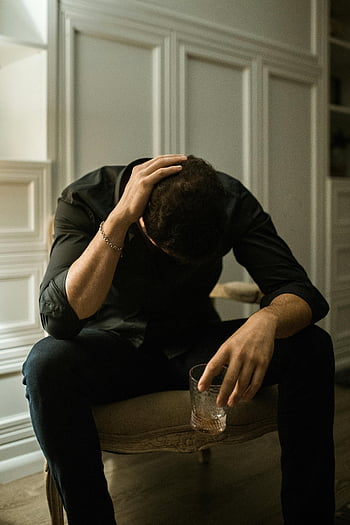 Problematisk mann, Svarte lange ermer, sitter på stolen, holder glass, mann i nød, hodet i hånden, innendørs innstilling, gjenspeiler ensomhet, drikke, sitter, innendørs scene