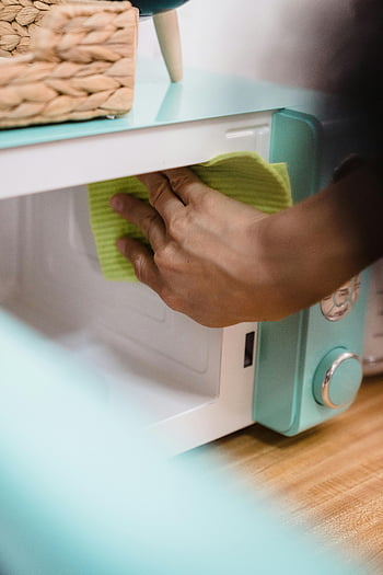 microwave cleaning, hand cleaning microwave, close-up cleaning, household chores, cloth cleaning, microwave oven, green cloth, kitchen cleaning, appliance cleaning, microwave maintenance, cleaning tips
