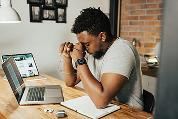 müder Mann, Augen reiben, sitzender Laptop, Heimarbeit, erschöpfter Mann, Hauptschreibtisch, digitale Geräte, Arbeitsprobleme, Büroermüdung, Arbeitsstress, entfernter Arbeiter