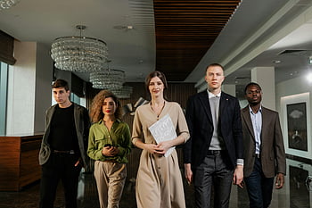 man in black suit, standing between women, diverse group, professionals, confidently walking, stylish office environment, modern office, business attire, group of people, office setting, professional group