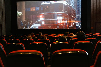 movie theater, cinema, people watching movie, large screen, seated audience, fire truck, movie scene, indoor theater, cinema seats, moviegoers, film screening