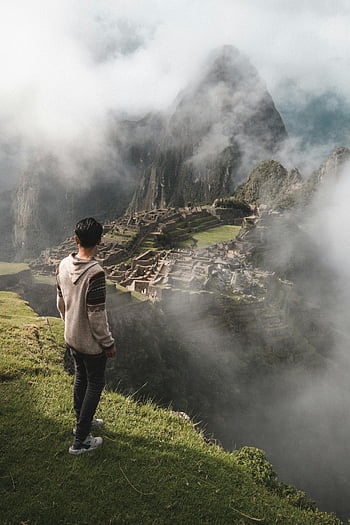 man standing on cliff, Machu Picchu, ancient ruins, misty landscape, cliff edge, travel photography, adventure travel, scenic view, Inca civilization, Peru tourism, natural wonder