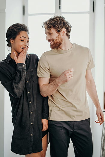 casal alegre, roupa casual, momento alegre, Mulher de camisa preta, Homem de camiseta marrom, configuração doméstica, Estilo casual, casal feliz, cena interna, ambiente descontraído, vida cotidiana