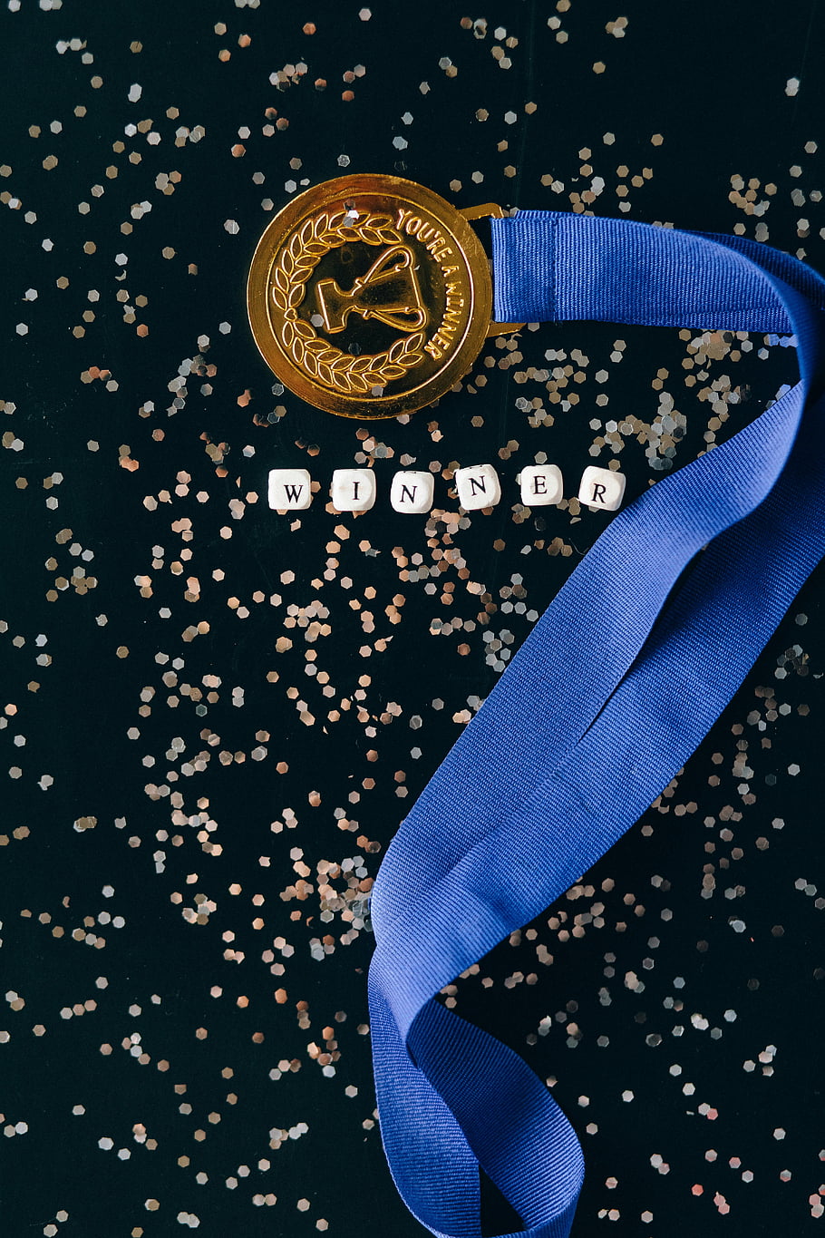 medaile, modrá stužka, černý povrch, vítězný text, lesk, detailní záběr, cena, trofej, oslava, konfety, vítězství