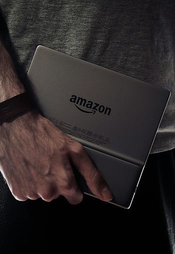 Amazon Kindle, e-book reader, man's hand, dimly lit, close-up, digital device, reading device, portable device, technology, handheld device, Amazon logo