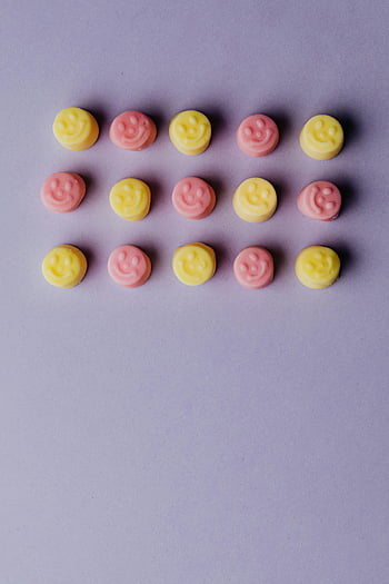 pink gummies, yellow gummies, smiley face gummies, colorful gummies, pastel purple background, candy arrangement, sweet treats, fun snacks, happy face candies, gummy candies, pastel colors