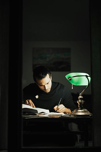 homme réfléchi, Écriture en cahier, en train d'étudier, bureau à domicile, homme concentré, Écriture au bureau, lampe verte, immergé dans l'étude, Lampe de bureau, environnement d'étude, espace de travail à domicile