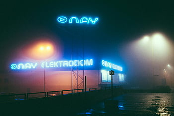 nay elektrodom, osvětlené značení, mlhavé noci, pouliční scény, neonová světla, světelné reklamy, náladová atmosféra, noční fotografie, městské krajiny, mokré dlažby, pouliční osvětlení