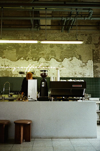kafé teller, retroinspirert kaffebar, moderne espressomaskin, Barista på jobb, kaffebar interiør, industriell design, vintage vegg, neon skilt, kaffebønner, bar telleren, avføring