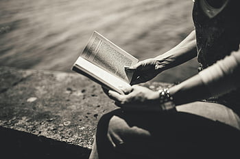 woman reading, book, outdoors, by water, monochrome, day time, sitting, enjoying, reading time, peaceful scene, black and white